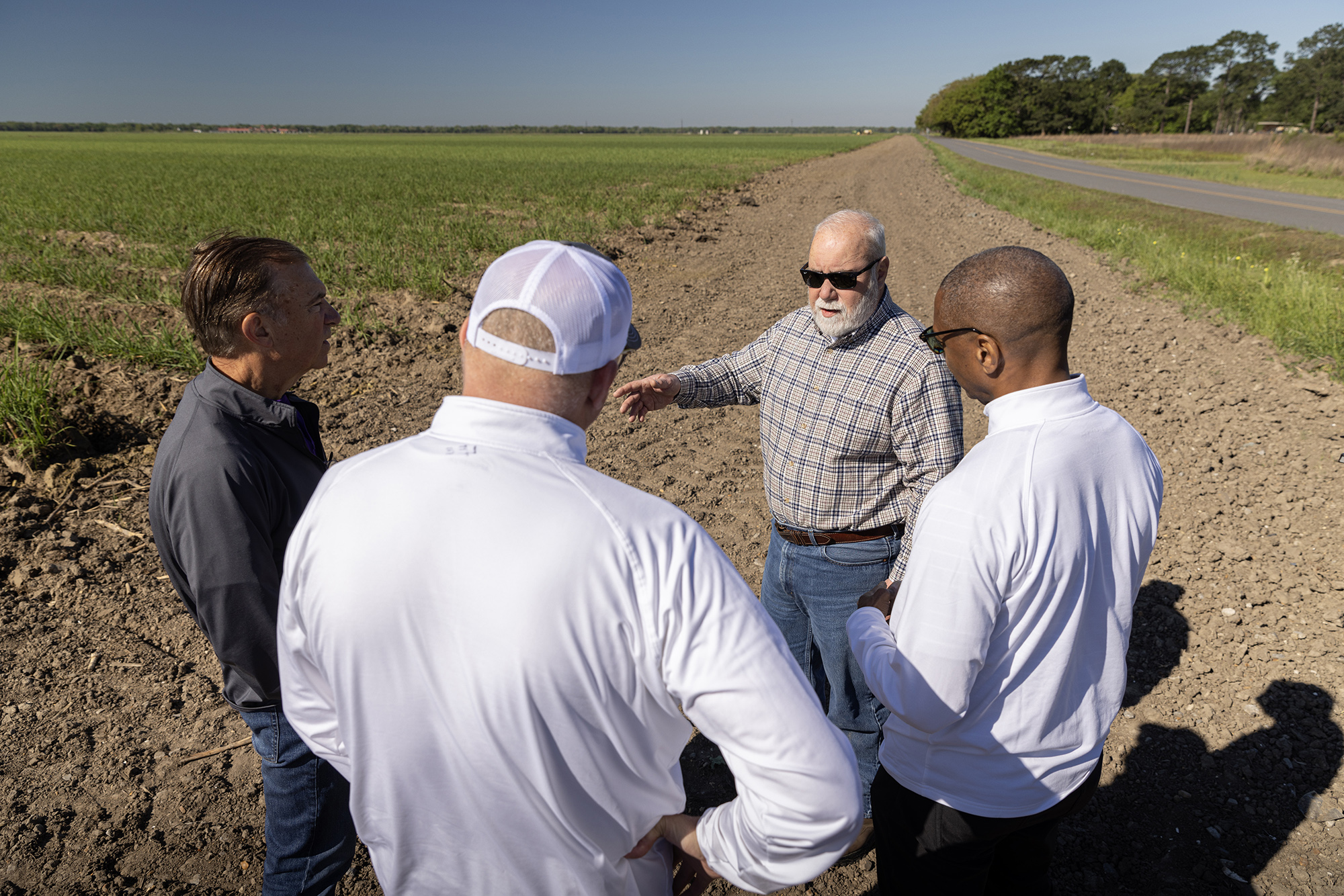 President Tate and others standing next to a sugarcane field