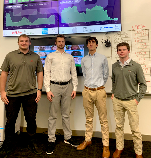 Team of four students in front of financial screen