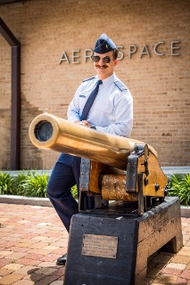 Austin Firmin in his uniform standing by a bronze cannon on campus