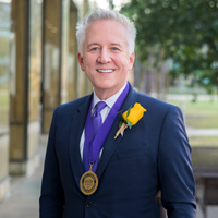 Stephen Toups wears a dark suit and a medal around his neck