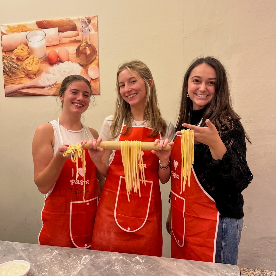 three students hold freshly made pasta in their hands
