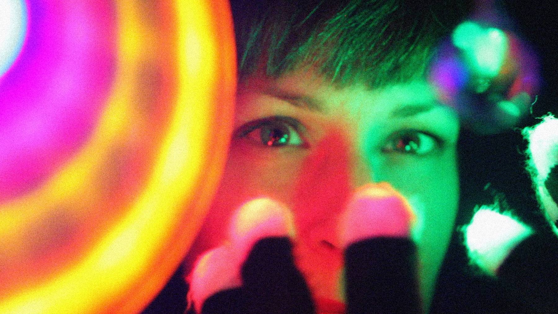 Close up on a young person face with an ethereal cast of rainbow colors.