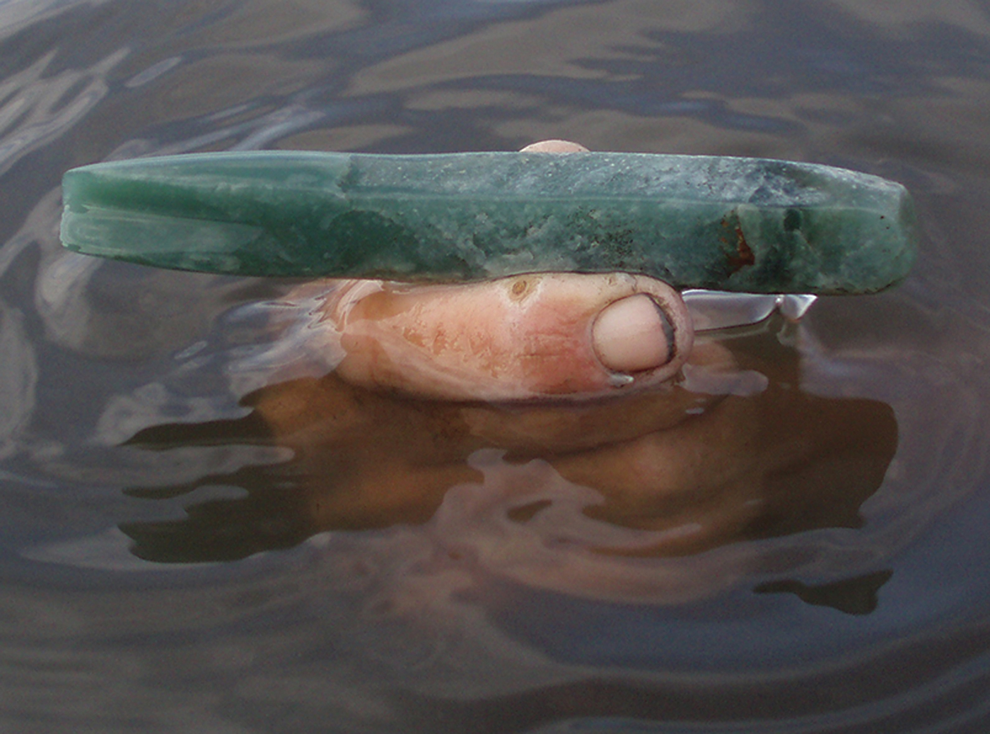 Photo of jadeite tool held in water.