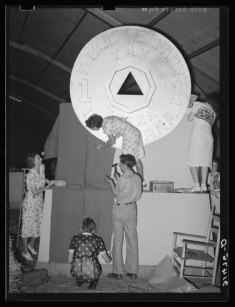 Historical black and white photograph of five people decorating a parade float